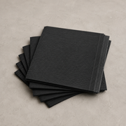 A stack of black textured paper napkins with a ribbed pattern, arranged on a neutral gray concrete-like surface.
Black Disposable Patient Bibs 125 PCS – Protective Tattoo Workstation Bibs