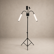 A black tripod floor lamp with two adjustable gooseneck arms and cylindrical white diffusers, shown against a neutral beige studio backdrop.