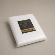 A package of Arrow brand white disposable cover sheets, sealed in clear plastic with a black and gold label, set against a neutral gray background.